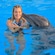 A woman crosses her arms over her chest while swimming with a dolphin